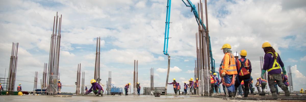 Wide shot of concrete company employees working with equipment in the background